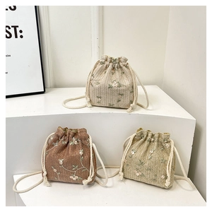 Dettaglio di tre borse a secchiello ricamate con coulisse in beige, marrone e verde
