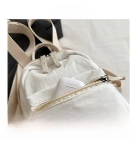 Detail of white nylon backpack front zip pocket with wireless earphone case inside