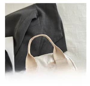 Close-up of wide beige woven handles and reinforced stitching on white travel backpack