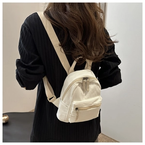 Detail of minimalist beige canvas backpack with adjustable straps and zipper pockets