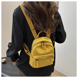Detail of a vibrant yellow canvas mini backpack with premium texture for casual travel