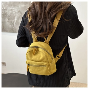 Close-up of bright yellow mini nylon backpack on model with adjustable straps