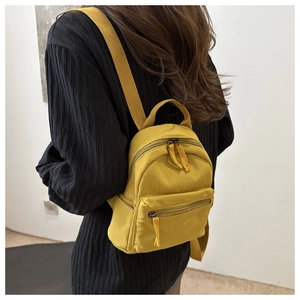 Close-up of a mustard yellow mini backpack featuring high-density nylon texture and zipper detail