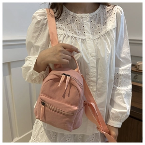 Close-up of pink canvas mini backpack showing detailed stitching and fabric straps