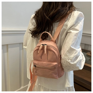 Pink minimalist mini backpack for women, shown on back in soft interior setting