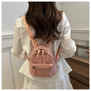 Pink mini backpack shown on model to demonstrate small size and casual style