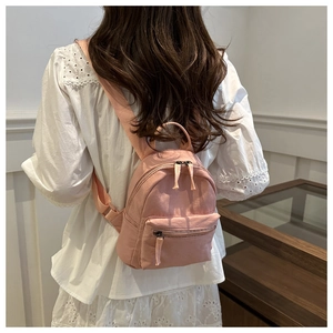 Pink mini backpack in wrinkled fabric shown on a model's back for casual travel