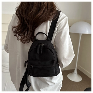 Detailed view of back-carried black nylon backpack showing adjustable straps and zipper