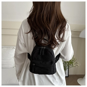 Detail of a minimalist black nylon mini backpack with high-quality zipper on a back view