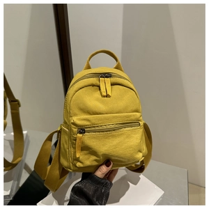 Ginger yellow nylon mini backpack held by hand showing compact size and texture