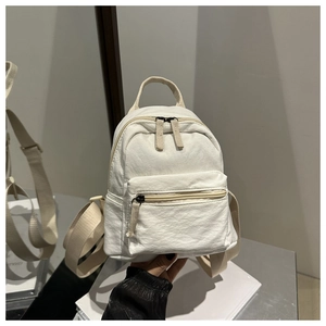 Close-up of white mini canvas backpack with textured fabric and zipper pocket details