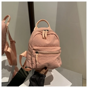 Detail of light pink mini nylon backpack with front zipper pocket and adjustable straps