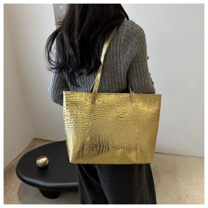 Large golden crocodile pattern tote bag shown over the shoulder in a minimalist room