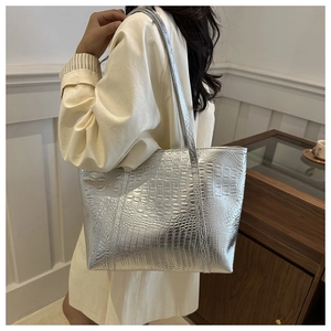 Detail of silver crocodile pattern tote bag with metallic texture and slender shoulder straps