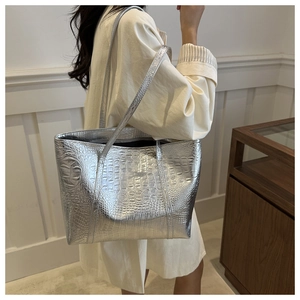 Detailed view of silver tote bag with crocodile embossing and metallic texture on model