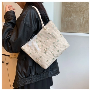 Détail du sac cabas brodé avec nœud en dentelle et texture tissée sur le mannequin