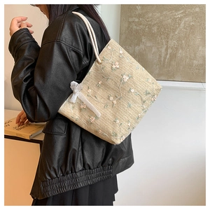 Détails de broderies florales et nœud en dentelle sur sac cabas tissé avec poignée