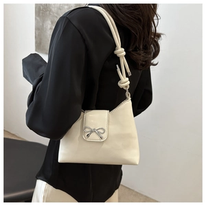 Détail du sac sous le bras en cuir blanc crème avec boucle noeud argentée et bandoulière