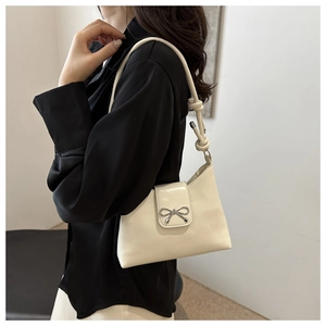 Vue latérale du sac sous le bras en cuir crème avec boucle noeud argenté sur modèle