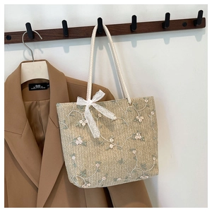 Détail d'un sac cabas tissé avec broderies florales et nœud élégant en dentelle blanche