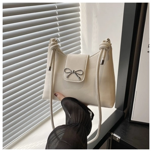 Gros plan du sac seau crème avec boucle nœud argenté et fine bandoulière en cuir