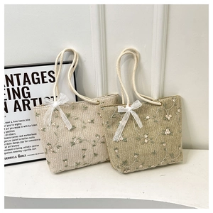 Détail de sacs cabas tissés avec broderie de vigne et nœud en dentelle sur anses en corde