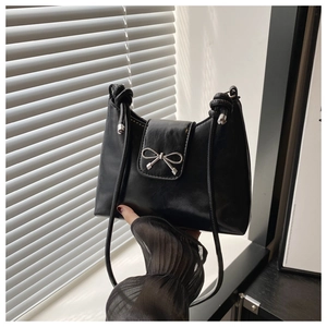 Détail d'un sac à bandoulière en cuir PU noir avec nœud argenté et poignée nouée chic