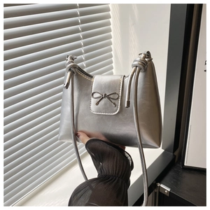 Détail du sac à bandoulière argenté métallisé avec bandoulière nouée et nœud décoratif en métal