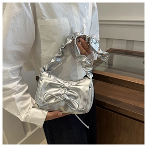 Detail of silver pleated crescent bag with bow decoration and scrunchie shoulder strap