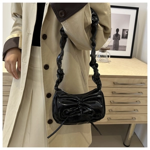 Detail of black glossy hobo bag with bow decoration and pleated ruffled strap