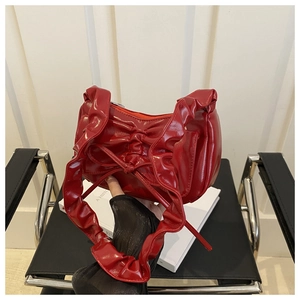 Detail of red patent leather crescent bag with bow decoration and pleated edges