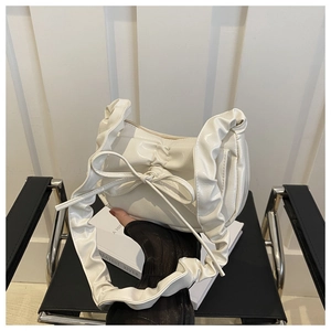 Detail view of a white bow crescent bag with ruffled edges and polished leather finish