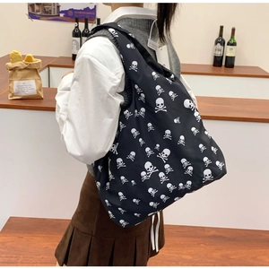 Detail van zwarte canvas shopper met witte schedelpatronen gedragen door een model