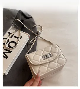 Detail of white quilted crossbody bag featuring gold metal clasp and leather chain strap