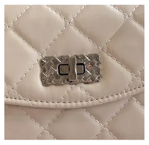 Close-up of golden rectangular twist lock with woven texture on beige leather bag