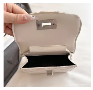 Interior detail of white quilted chain bag showing silver twist lock and inner compartment