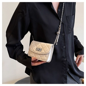Detailed view of beige quilted handbag with crystal buckle and golden chain strap