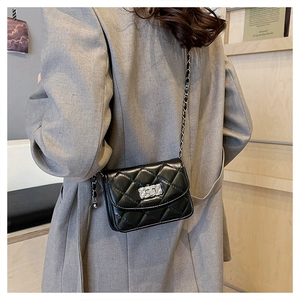 Detail of black quilted leather mini crossbody bag with silver clasp and chain strap
