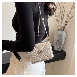 Silver quilted mini crossbody bag with metal woven buckle shown in a modern interior setting