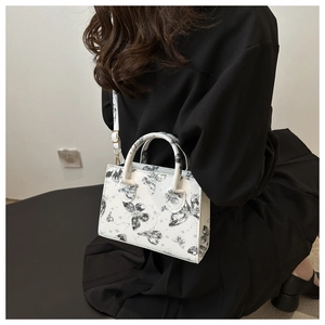 Close-up of white crossbody bag with butterfly prints and gold-tone metal hardware