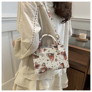 Detail of vintage square shoulder bag featuring butterfly prints and adjustable strap