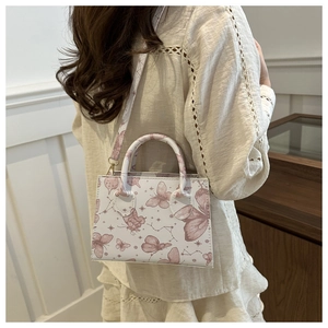 Detail of white square handbag with pink butterfly pattern and adjustable shoulder strap