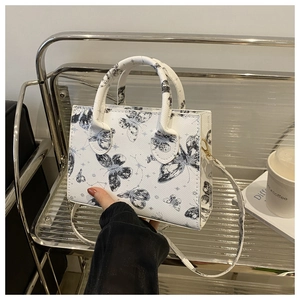 Détail du sac à main blanc à grain croisé avec imprimé papillon et poignée ronde