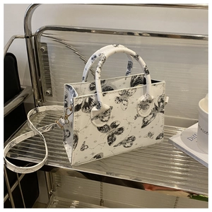 Détail de l'imprimé papillon et étoile sur le cabas blanc en similicuir avec bandoulière