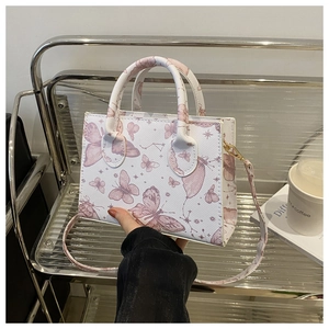 Gros plan détaillé d'un sac à bandoulière blanc avec imprimés papillons roses et cuir texturé