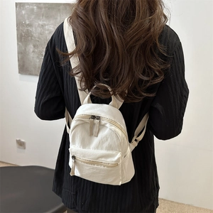 Minimalist beige canvas mini backpack for women showing back view on a model