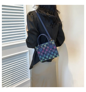 Detail view of multicolored woven texture with blue leather straps on the small square bag