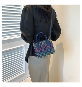 Detail of colorful woven checkered mini bag with frayed denim edges and golden hardware