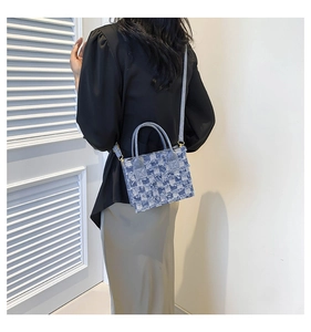 Blue denim checkered woven crossbody bag shown from behind with a long shoulder strap