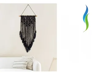 Macro view of hand-woven black macrame wall hanging with feather accents and wood rod